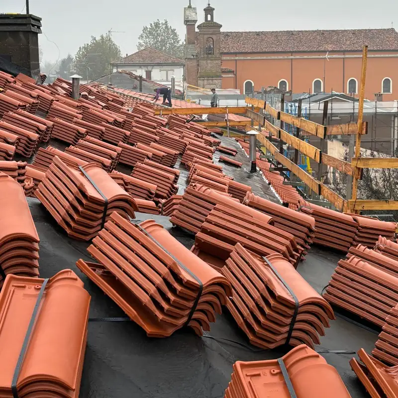 Guaina nera stesa sul tetto e pile di tegole nuove pronte per la posa