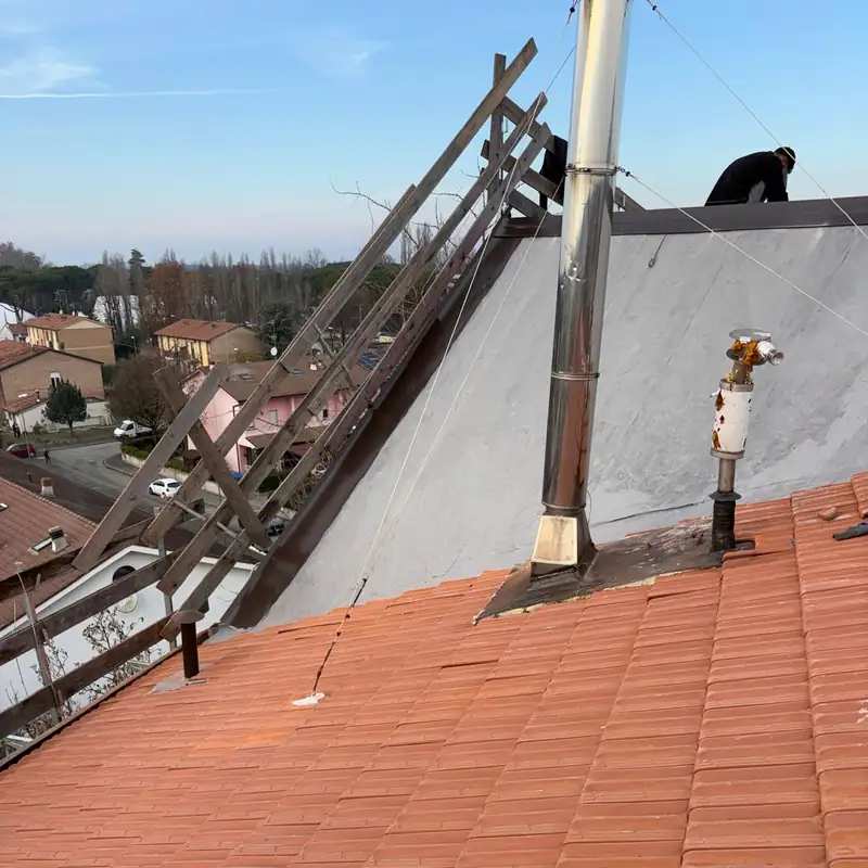 Tetto con tegole nuove e camino in acciaio, un operaio al lavoro sullo sfondo
